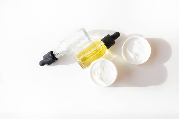 Drop bottle with oil, cream in a white jar. Skin care concept - Photo, Image