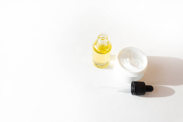 Drop bottle with oil, cream in a white jar. Skin care concept - Photo, Image