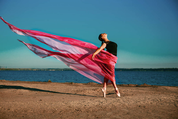mooi meisje op het strand met een rode doek in haar handen - Foto, afbeelding