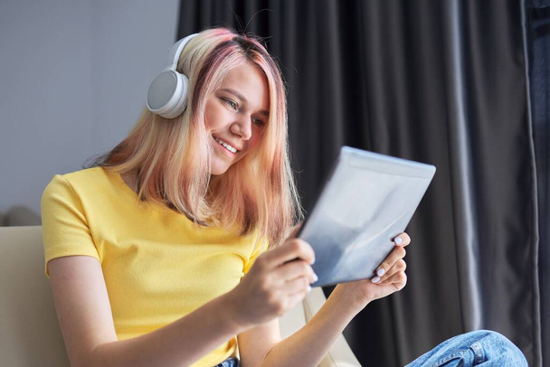 High school student teenager girl in headphones with digital tablet at home - Foto, imagen