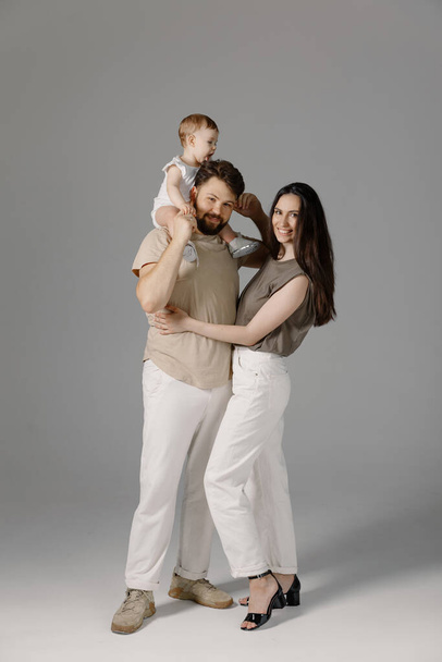 Foto della giovane famiglia felice con il bambino che rimane sul pavimento isolato su uno studio di sfondo bianco. Stile di vita, felicità, amore - Foto, immagini