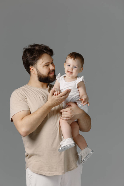 Батько і донька - посміхаються в студії, ізольовані на сірому фоні. Молода дівчина сидить на плечах свого тата, стиль життя
 - Фото, зображення