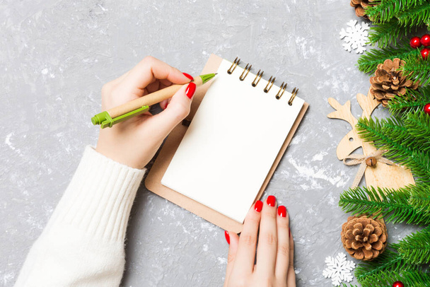 Top kilátás a női kézírás egy notebook cement karácsonyi háttér. fenyőfa és ünnepi dekoráció. Kívánságlista. Újévi koncepció. - Fotó, kép