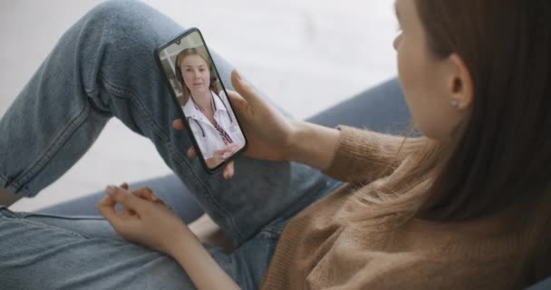 Жінка використовує медичний додаток на смартфоні, консультуючись з лікарем через відеоконференцію. Жінка використовує онлайн чат, щоб розмовляти з сімейним терапевтом і перевіряє можливі симптоми під час пандемії коронавірусу
. - Кадри, відео