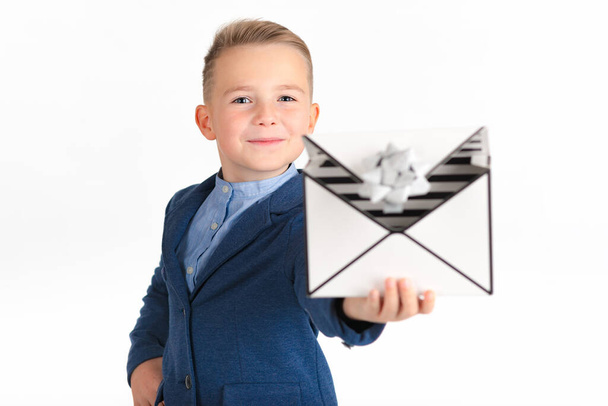 Счастливый маленький улыбчивый мальчик, выглядывающий вперед и смеющийся, открывая коробку с презентациями, как у мужчины Леттера. Изображение разложено на белой спине.. - Фото, изображение
