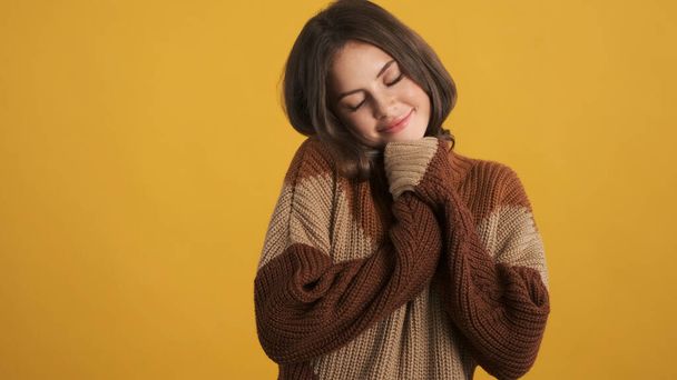 Pretty brunette girl in cozy knitted sweater cutely posing on camera over colorful background - Photo, Image