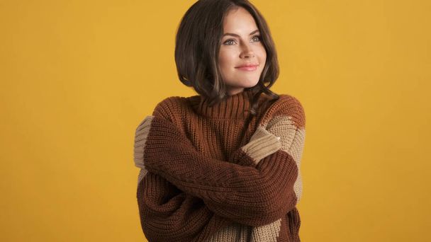 Gorgeous cute brunette girl in cozy knitted sweater dreamily looking away over colorful background - Φωτογραφία, εικόνα