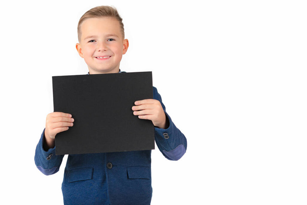 Happy exited caucasian young boy showing and displaying blank black board ready for your text or product.White background isolated. - Photo, Image