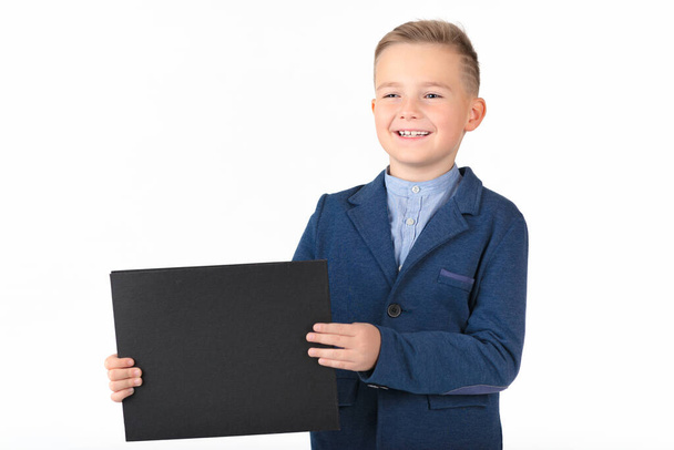 Feliz chico caucásico saliendo mostrando y mostrando tablero negro en blanco listo para su texto o producto.Fondo blanco aislado. - Foto, Imagen