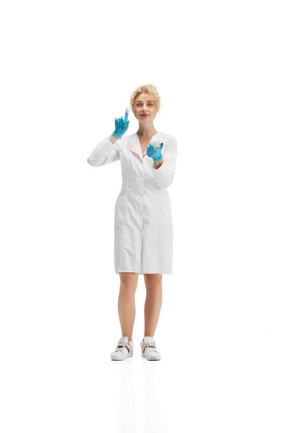Portrait of female doctor, nurse or cosmetologist in white uniform and blue gloves over white background - Valokuva, kuva