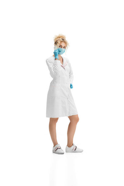 Portrait of female doctor, nurse or cosmetologist in white uniform and blue gloves over white background - Photo, Image