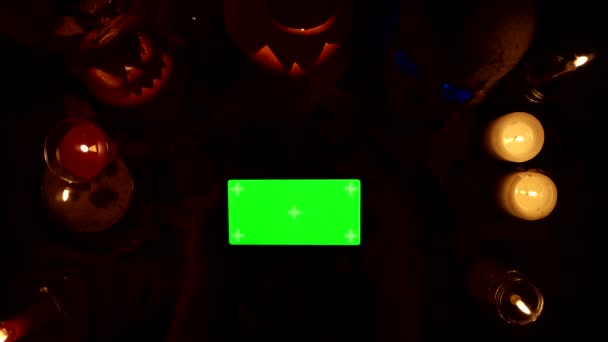 Παιχνίδι άνθρωπος σε οριζόντια smartphone με πράσινη οθόνη στο παρασκήνιο του Halloween διακόσμηση - Πλάνα, βίντεο