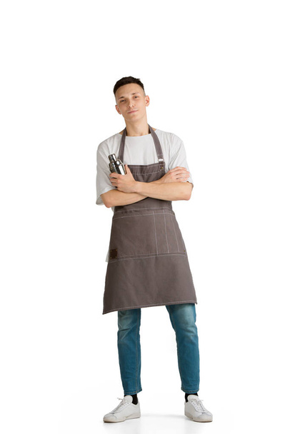 Isolated portrait of a young male caucasian barista or bartender in brown apron smiling - Foto, afbeelding