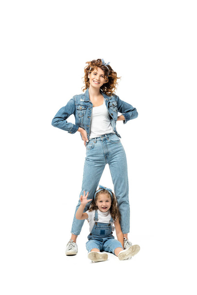 mother and daughter in denim outfits posing and smiling isolated on white - Foto, imagen