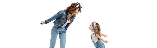 mother and daughter in denim outfits looking at each other isolated on white, panoramic shot - Foto, afbeelding