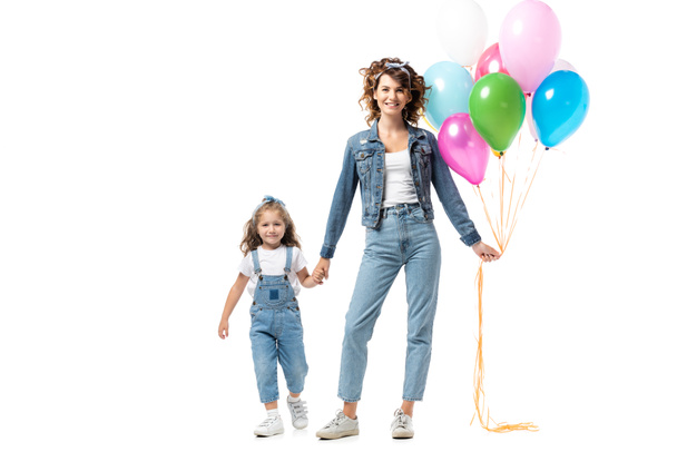 mother and daughter in denim outfits with colorful balloons holding hands isolated on white - Foto, Imagen