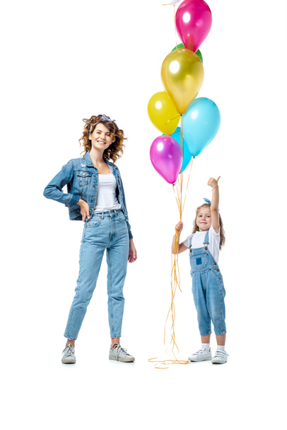 mother near daughter with colorful balloons showing thumb up isolated on white - Fotó, kép