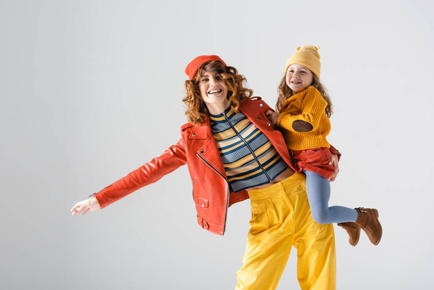 mother and daughter in colorful red and yellow outfits isolated on grey - Fotó, kép