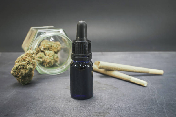 Glass bottle with CBD oil and hemp leaves on black wood background. Organic and natural hemp-based cosmetic and beauty products. Medical cannabis concept. Still life. Relaxing incense background. - Foto, imagen