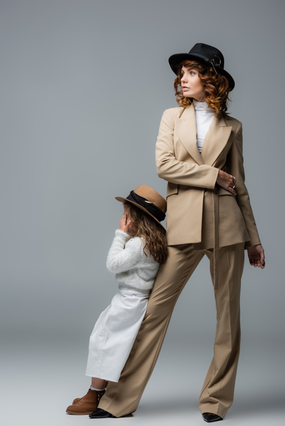 elegant mother and daughter in white and beige outfits posing on grey - Photo, Image