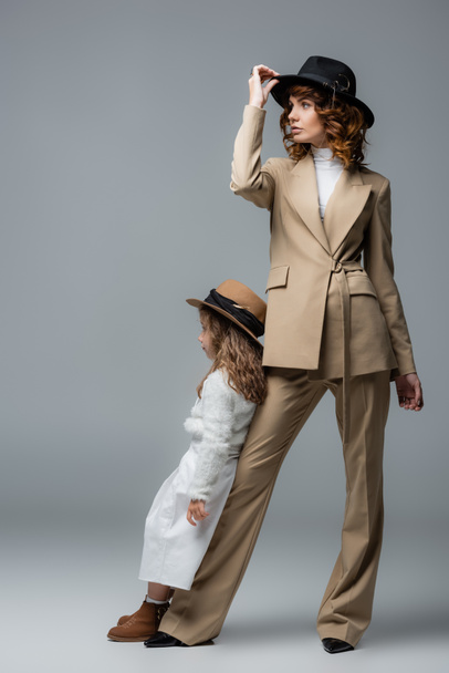 elegantní matka a dcera v bílých a béžových oblečení pózují na šedé - Fotografie, Obrázek