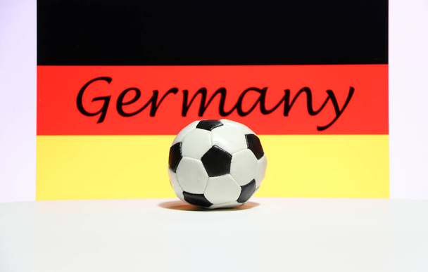 白い床に小さなサッカーとドイツの背景のテキストとドイツの国旗。スポーツの概念. - 写真・画像