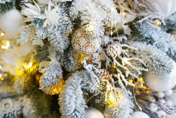 Красивый цвет рождественских украшений висит на рождественской елке с блестящими бликами - Фото, изображение