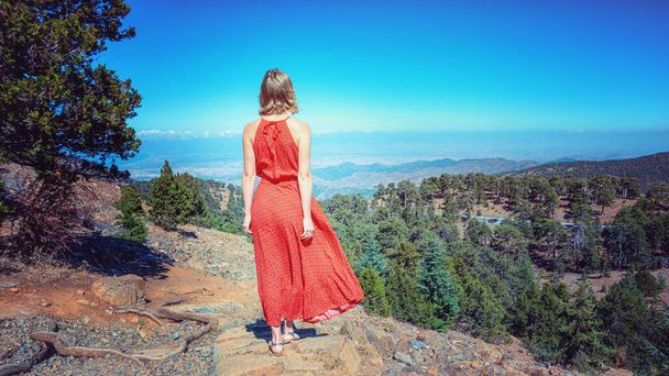 Fashionable girl on a mountain top on Cyprus wearing red dress - Photo, Image