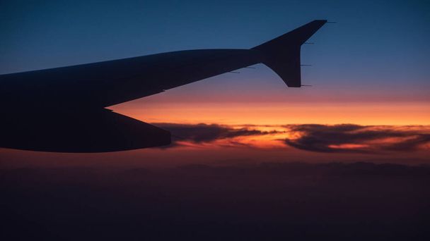 Schöne subtile Farben des Sonnenuntergangs aus einem Flugzeugfenster aufgenommen - Foto, Bild
