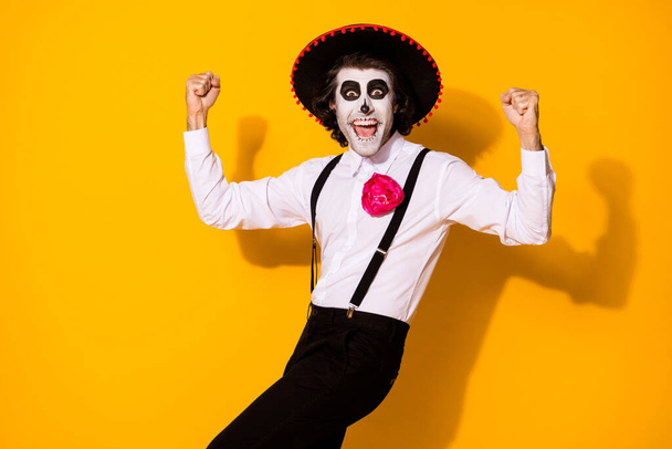 Photo portrait of cheerful crazy nice handsome funny mexican guy in traditional costume raising fists up isolated bright color yellow background - Foto, imagen
