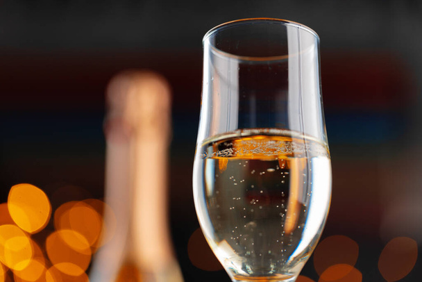 Champagne glass on blurred garland lights background - Foto, Imagem