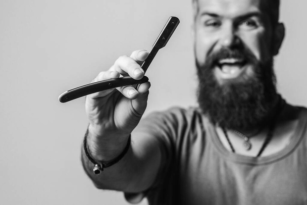 Bearded man with stylish hairdo. Barbershop advertising. Barber man holds straight razor. Brutal man with vintage straight razor. Barber shop concept. Vintage barbershop and shaving. Black and white. - Photo, Image