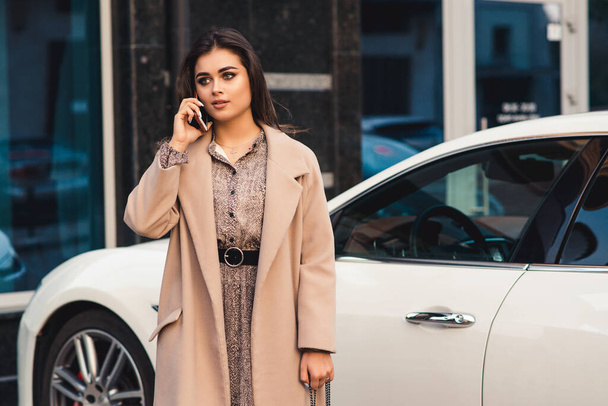 Businesswoman talking on mobile phone with client. Fashionable pretty woman with makeup and trendy hairstyle. Female using phone outside. Fashion, people, lifestyle. - Photo, Image