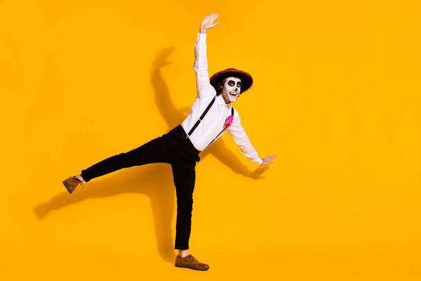 Full length photo of spooky zombie guy dance pretend fly airplane pose festival raise hands excited wear white shirt rose death costume sombrero suspenders isolated yellow color background - Photo, image