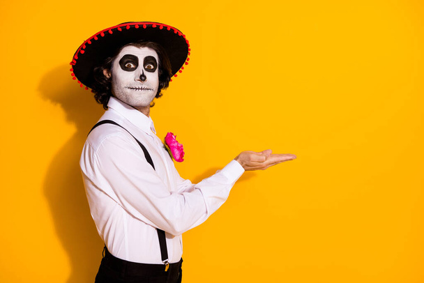 Profile photo of creepy ghost guy hands hold empty space propose handmade potion limited edition wear white shirt rose sugar skull death costume suspenders isolated yellow color background - Photo, Image
