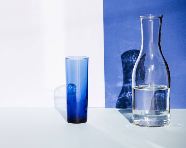 Transparent blue glass and water bottle in sunlight. - Foto, immagini