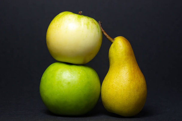 Фрукт на черном фоне. Груша и яблоки рядом друг с другом. Здоровые фрукты - Фото, изображение
