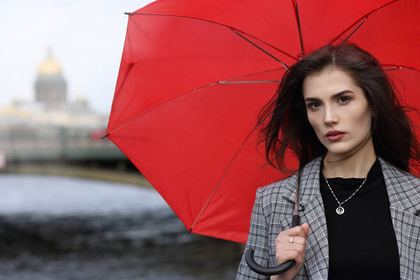 Portrait of a beautiful girl in a pantsuit with a red umbrella on a walk in St. Petersburg - Valokuva, kuva