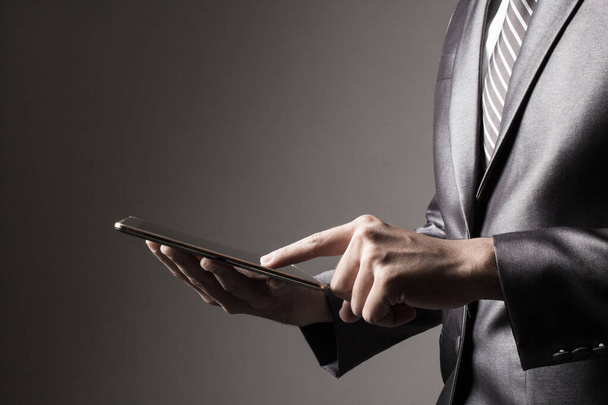 Businessman  touching smartphone on black background - Photo, image