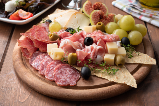 Platte mit leckerem italienischen Aufschnitt, Käse und frischem Obst  - Foto, Bild