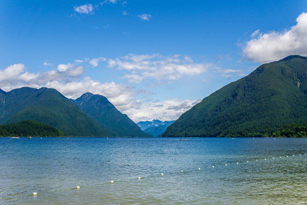 blue mountain lake with green mountains blue sky and white clouds. - 写真・画像