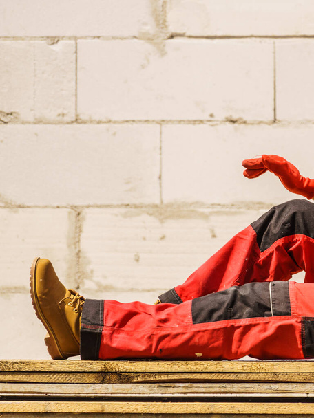 Unrecognizable person on construction site wearing protective worker red black pants trousers - Фото, изображение