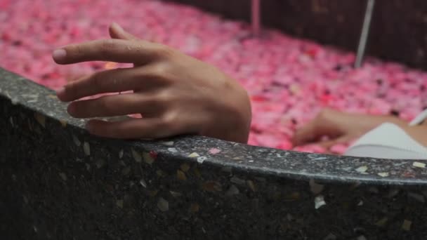 relax in bath with petals, woman is lying in water - Footage, Video