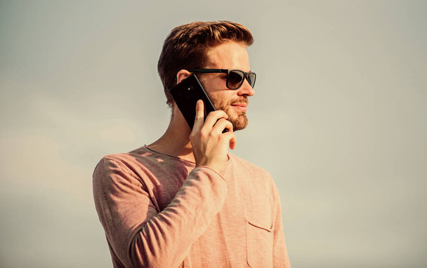 Important mobile conversation. Man mobile call. Stay in touch. Mobile call concept. Application and internet. Hipster wear sunglasses hold mobile phone sky background. Hipster smartphone call - Photo, image