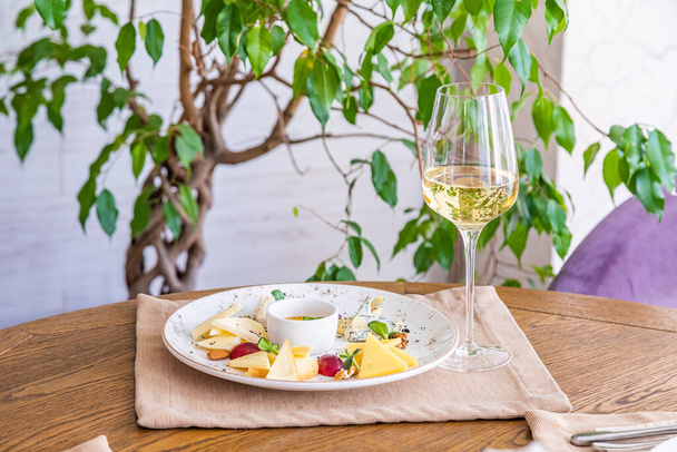 cheese platter. A plate with a variety of cheeses. Snacks. Glass of wine with cheese. - Foto, Imagem