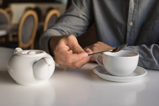 Der Kerl trinkt Tee, während er in einem Café sitzt - Foto, Bild