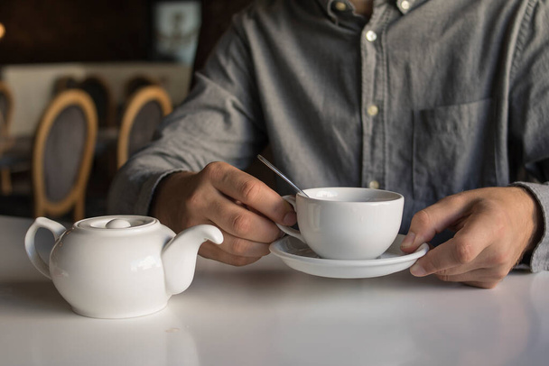 El tipo está bebiendo té mientras está sentado en un café. - Foto, imagen