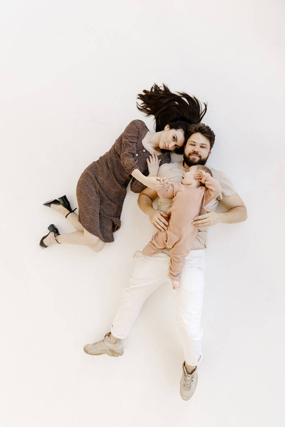 Vista de ángulo alto desde arriba de una familia feliz acostada en el suelo blanco, aislada - Foto, imagen