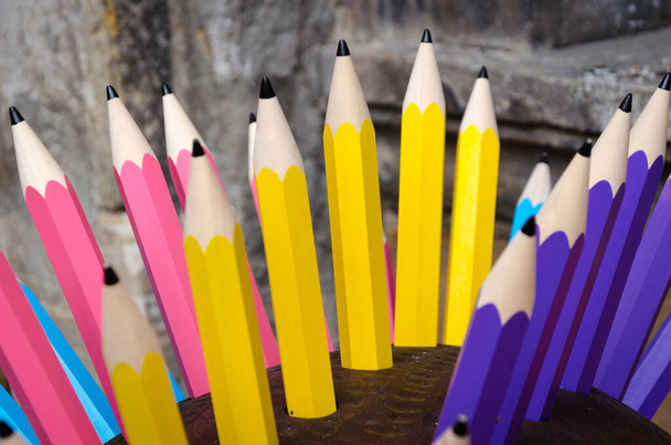 Διακοσμητικός σχεδιασμός από μεγάλα ξύλινα χρωματιστά μολύβια καρφωμένα σε μια βάση - Φωτογραφία, εικόνα