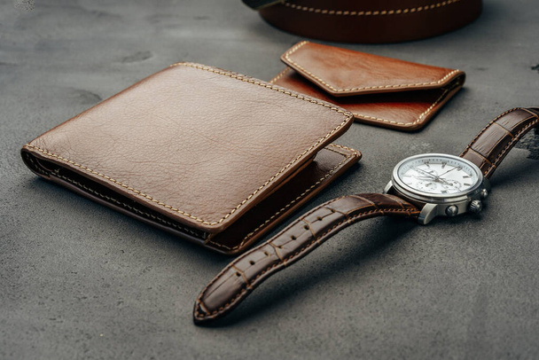 Male watch and leather wallet on dark grey surface - Foto, Imagen